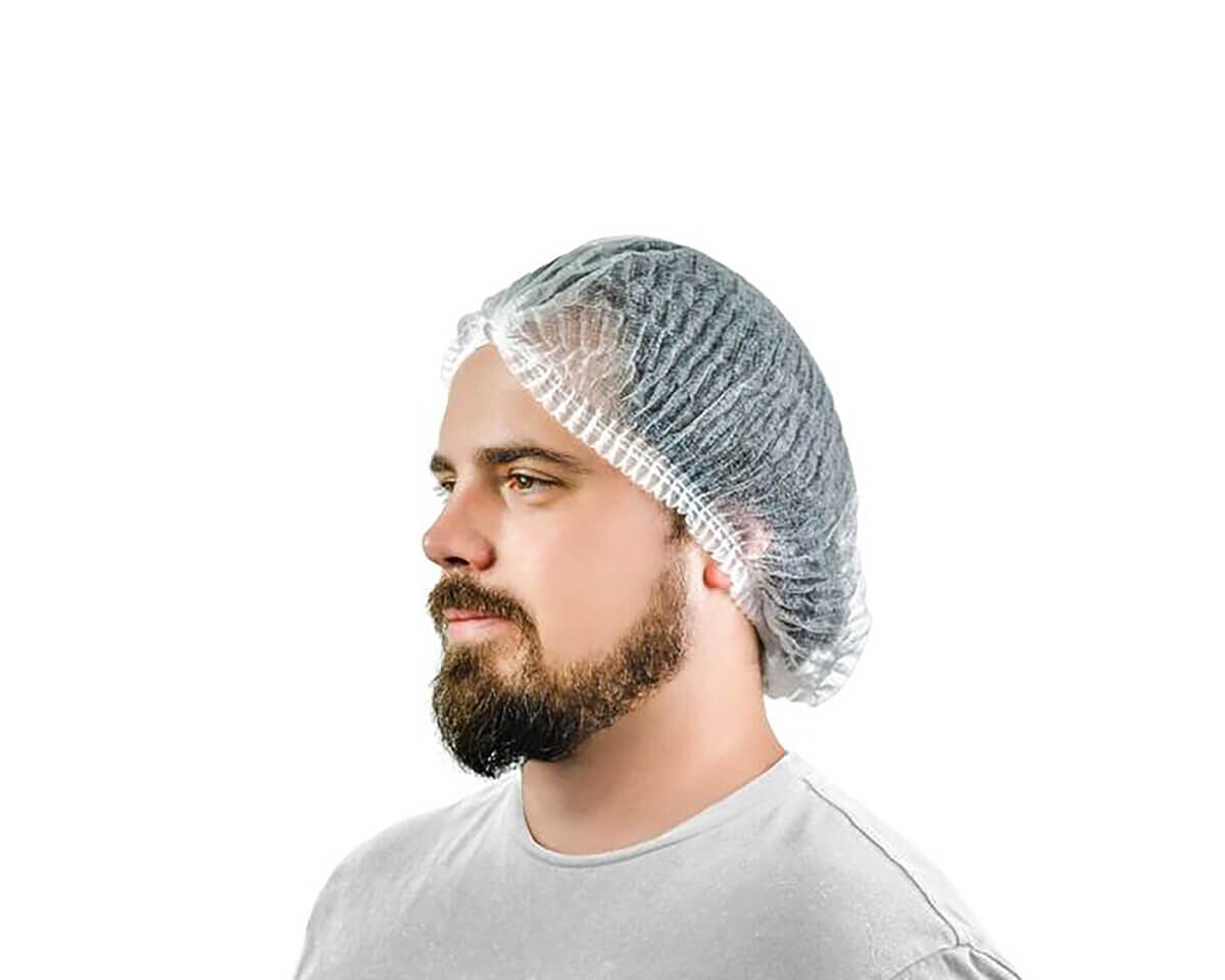 Person wearing a white bouffant cap with gathered elastic, side view