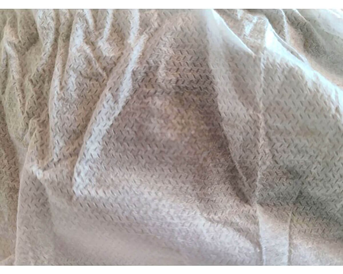 Detailed close-up of the white three-layer SMS fabric used in the International Enviroguard shoe cover