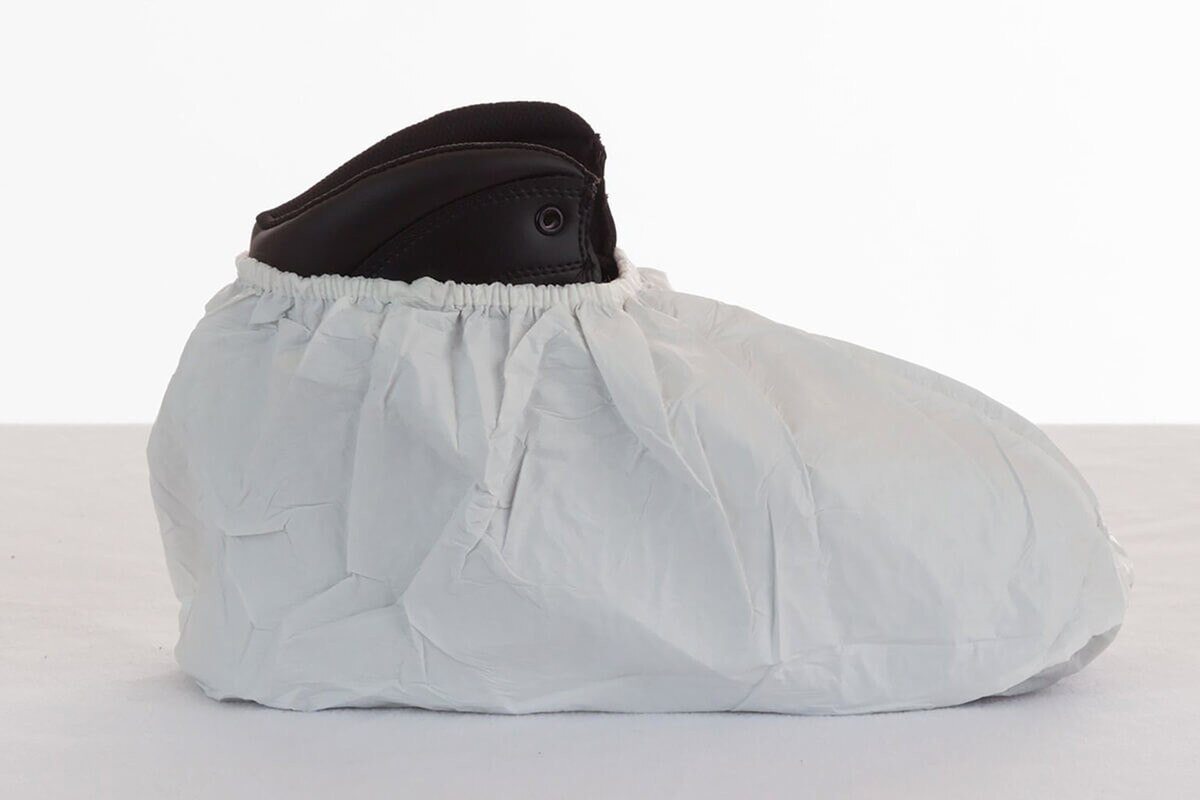 Opposite side view of the International Enviroguard sterile white shoe cover worn over a black shoe