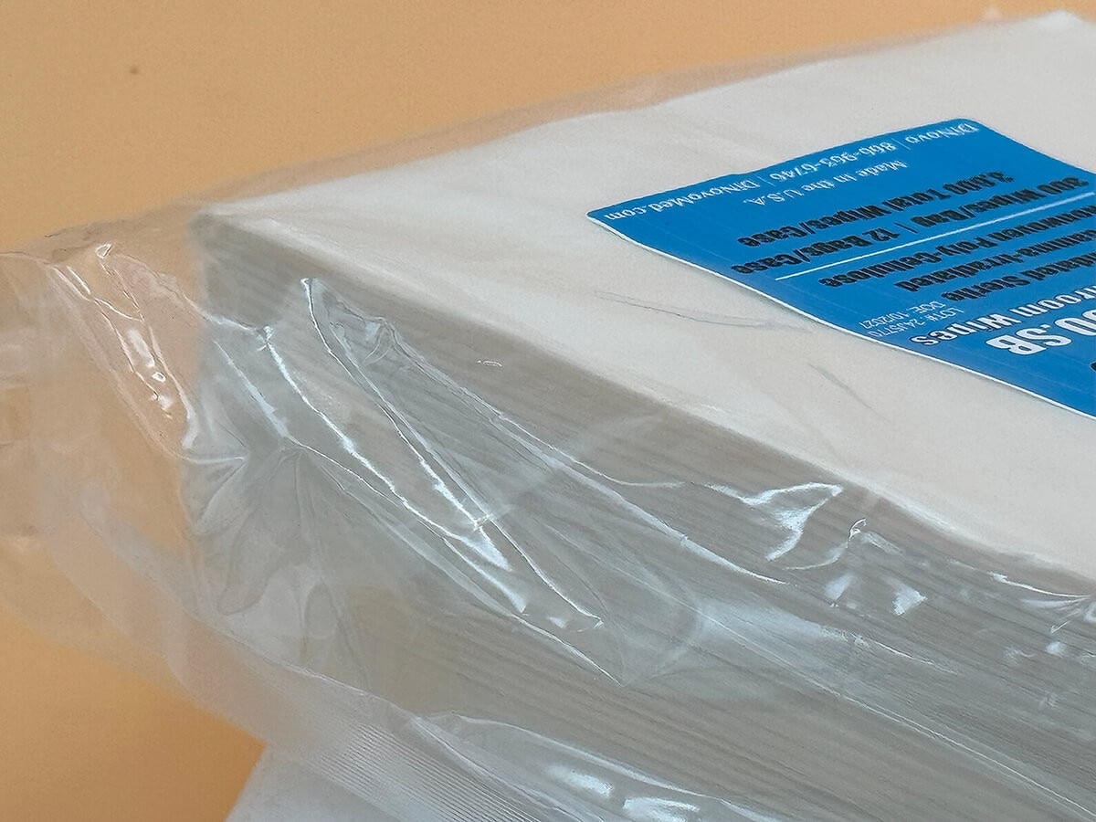 Close-up image of corner of packaged AstroWipe wipes showing thickness and poly-cellulose layers beneath plastic