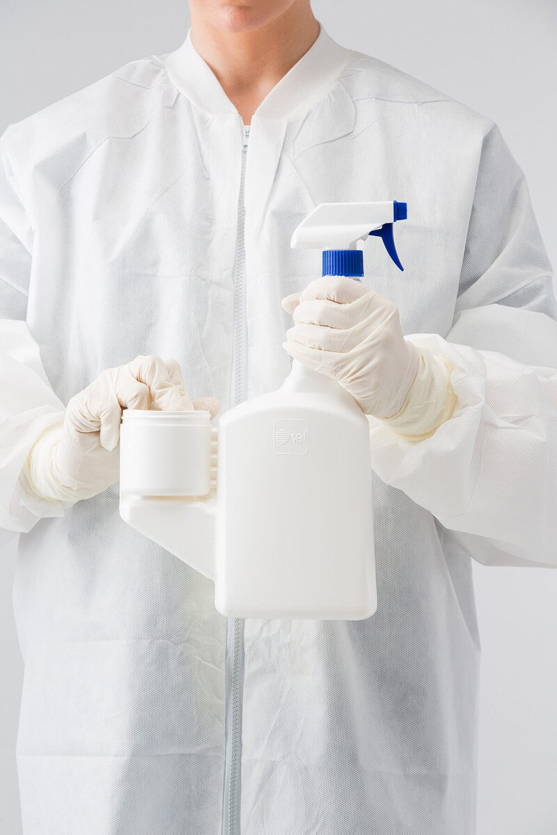 Gloved operator holding DECON-CYCLE II SimpleMix trigger spray bottle and accessing attached dilution cup.