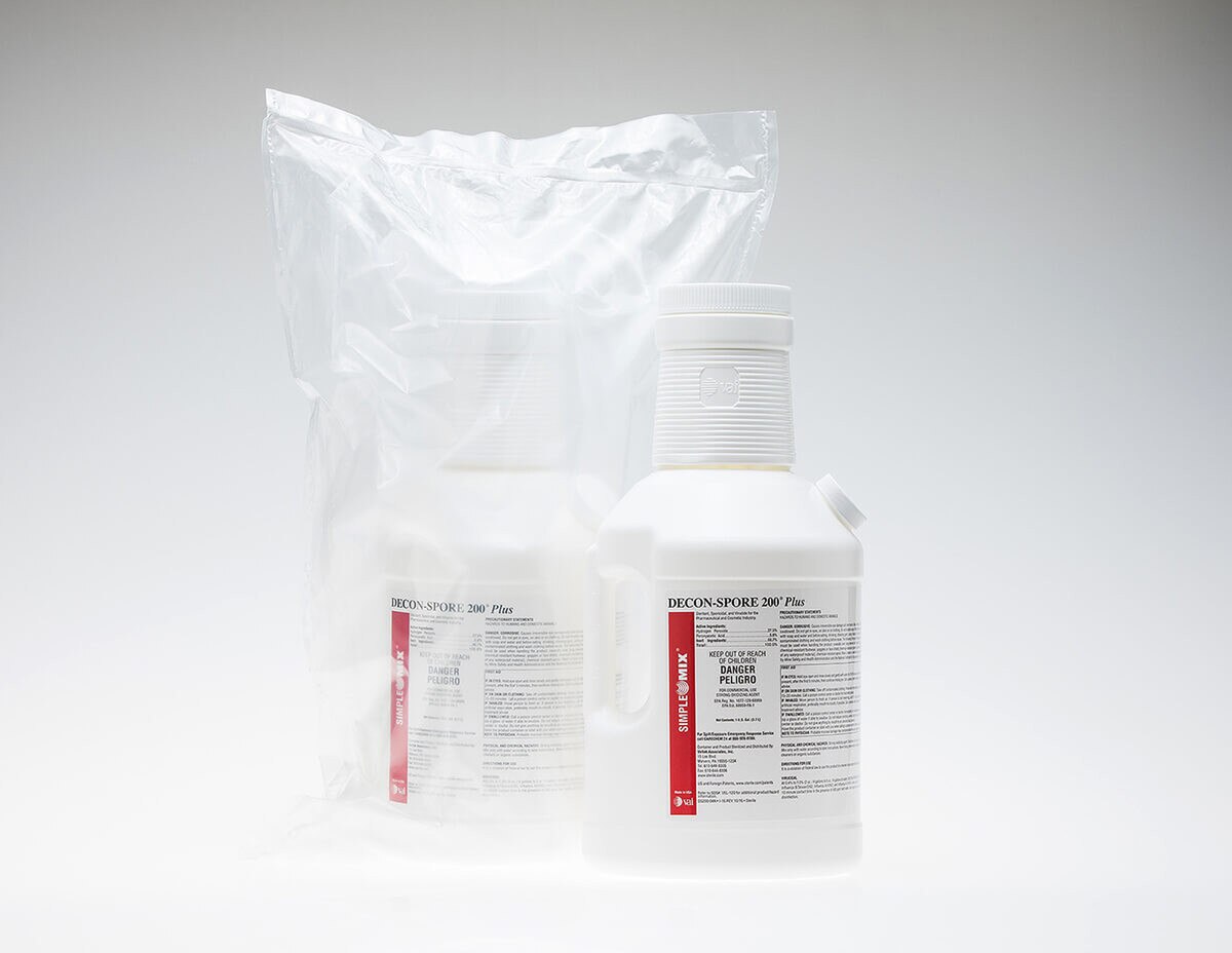 Two DECON-SPORE 200 Plus 5% bottles side by side, one sealed in a sterile bag and one unbagged on a reflective white surface.