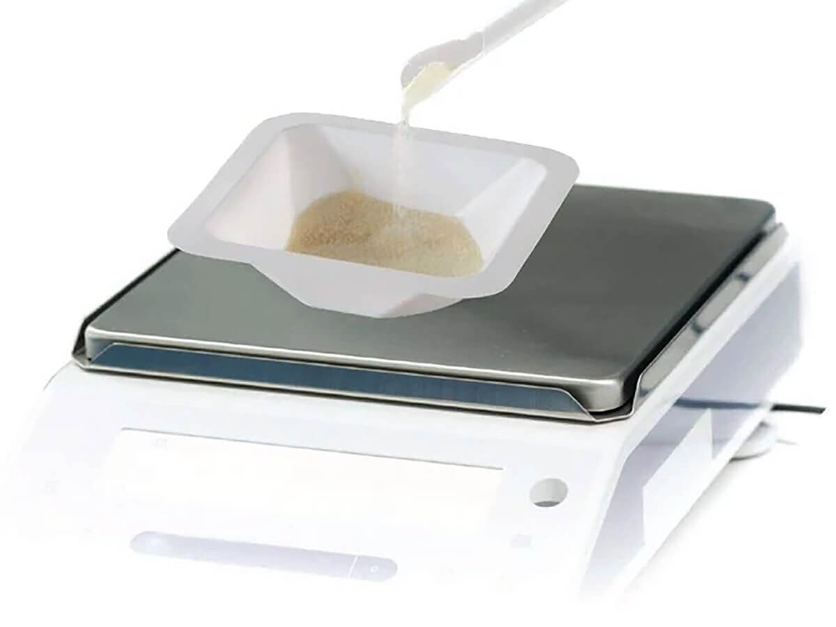 Heathrow Scientific 10 mL white anti-static weigh boat holding powder on a digital laboratory balance