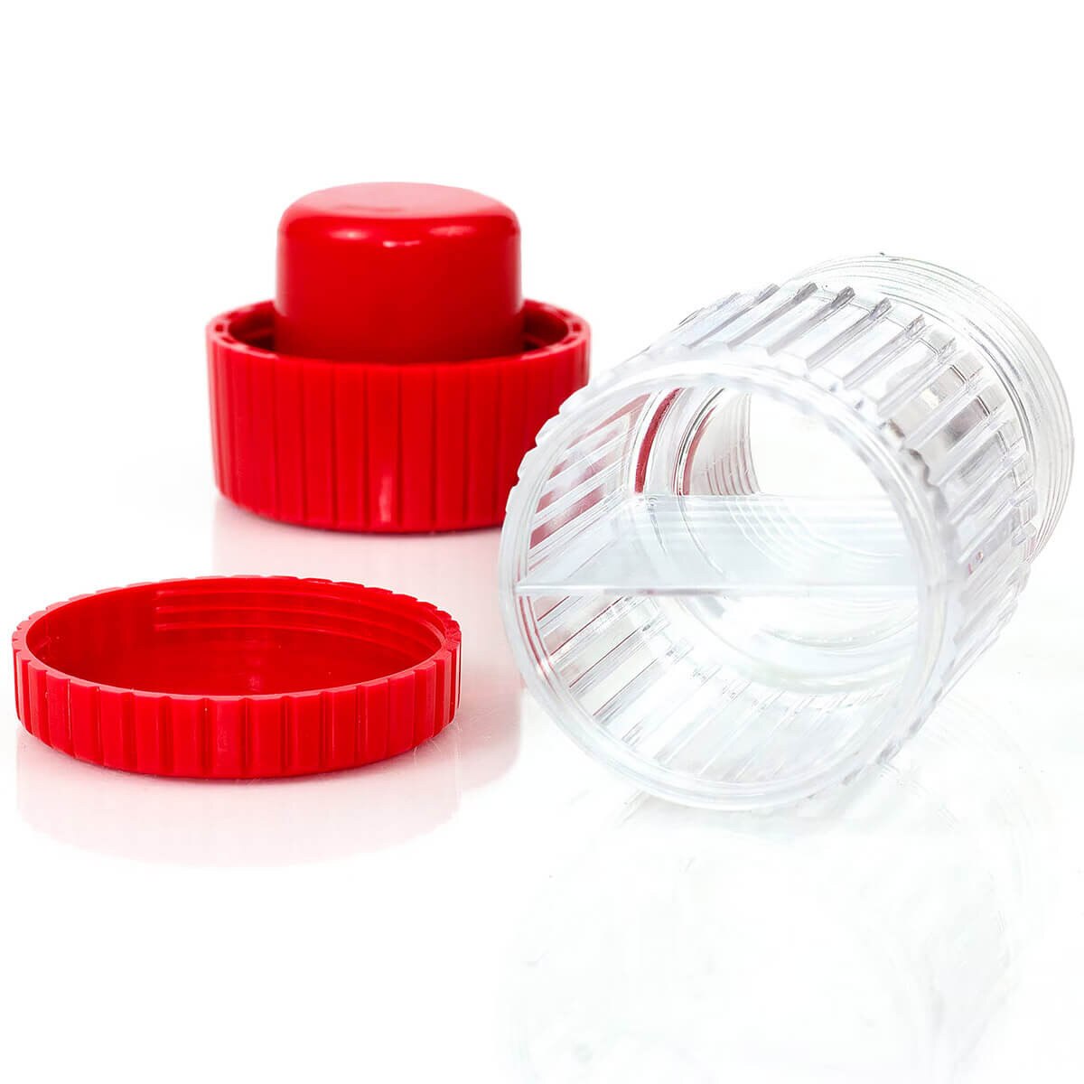 Disassembled HealthSmart pill crusher showing the red crushing cap, clear body, and storage lid